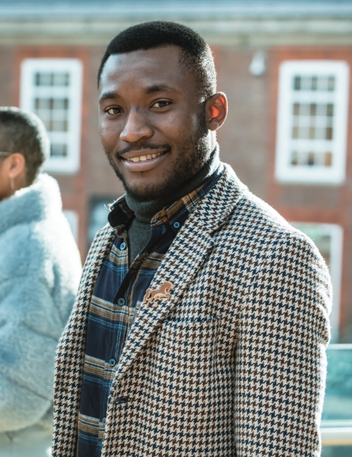 Raphael (Middlesex University postgraduate student) smiling in the top floor Mezzannie of the college building